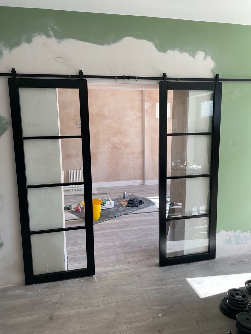 Pair of black-framed glass sliding barn doors fitted between two reception rooms