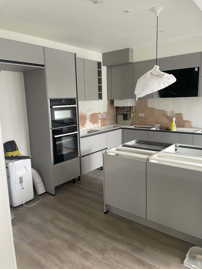 Handleless grey kitchen units being installed with built-in Bosch appliances