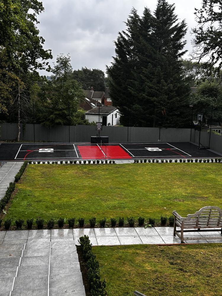 Private sports court installed in a Hadley Wood EN4 back garden by Dukes London — black tarmac with red basketball key and full line markings