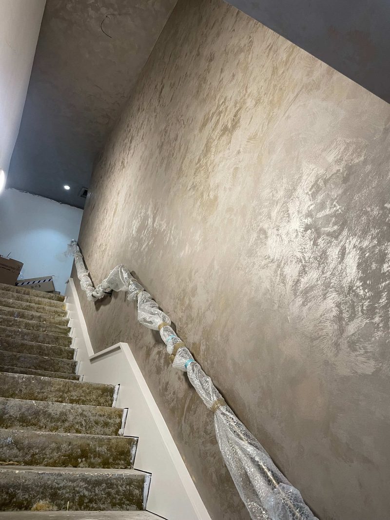 Hand-applied polished Venetian plaster on a stairwell wall, ready for finishing